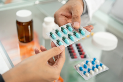 pharmacist handing pill package to patient while answering questions about prescription medications