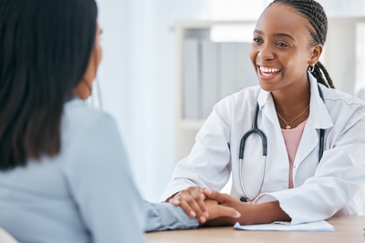 smiling pharmacist holding hand of patient during wellness consultation