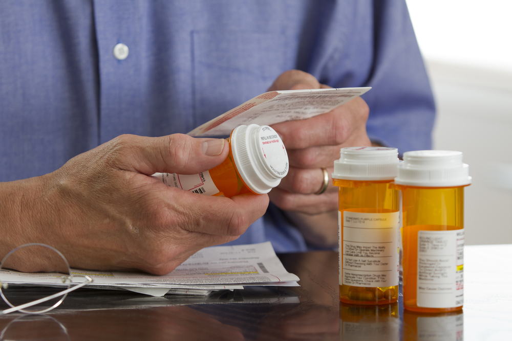 older man checking labels on prescription medications