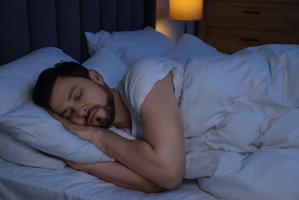 man sleeping in bed in darkened room